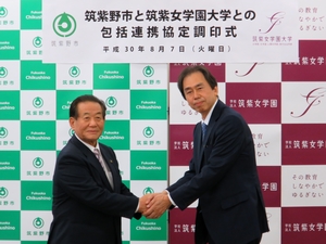 握手を交わす藤田市長（左）と中川学長（右）の画像